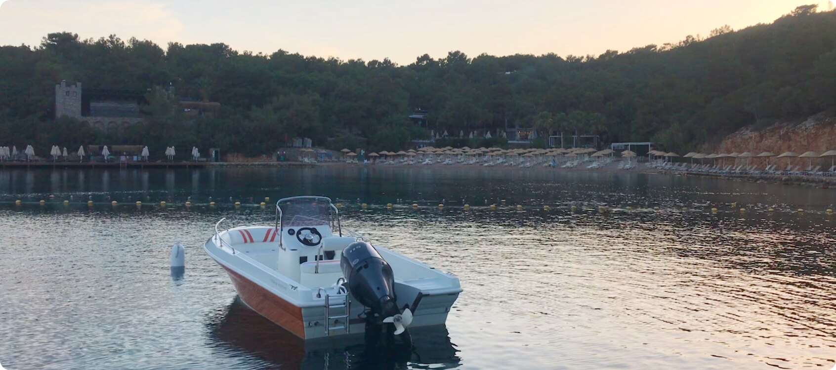 Photo of a small speedboat on a lake, surrounded by trees.